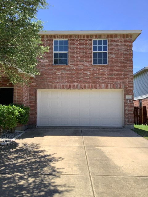 a white garage door in front of a brick house